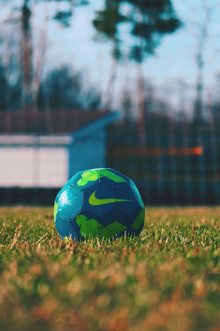 Close-up of a blue and green soccer ball on a grass field, perfect for sports themes.